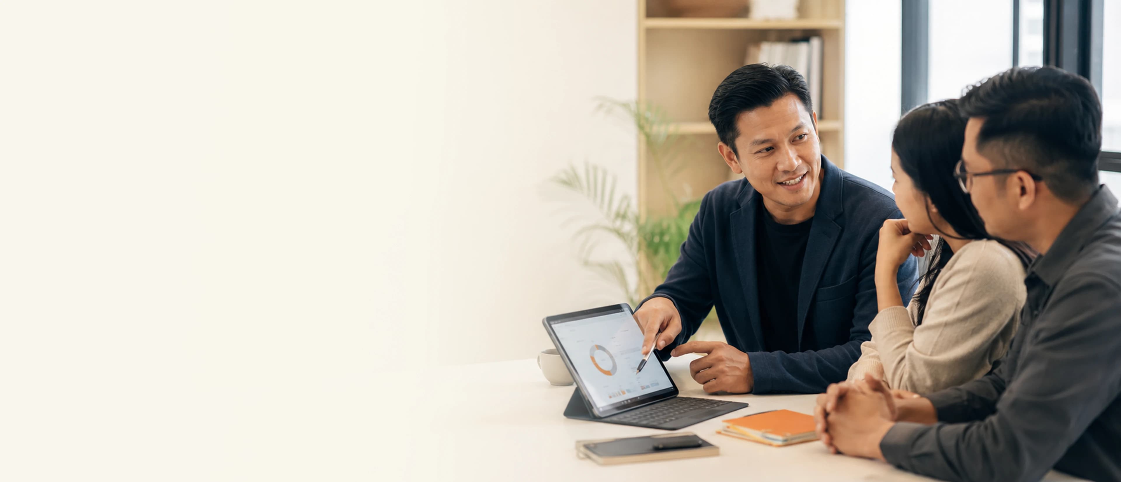Professionals collaborating at a desk with a tablet in a bright office